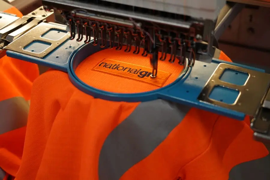 Nakış makinesinde firma logosu işlenen turuncu iş kıyafeti